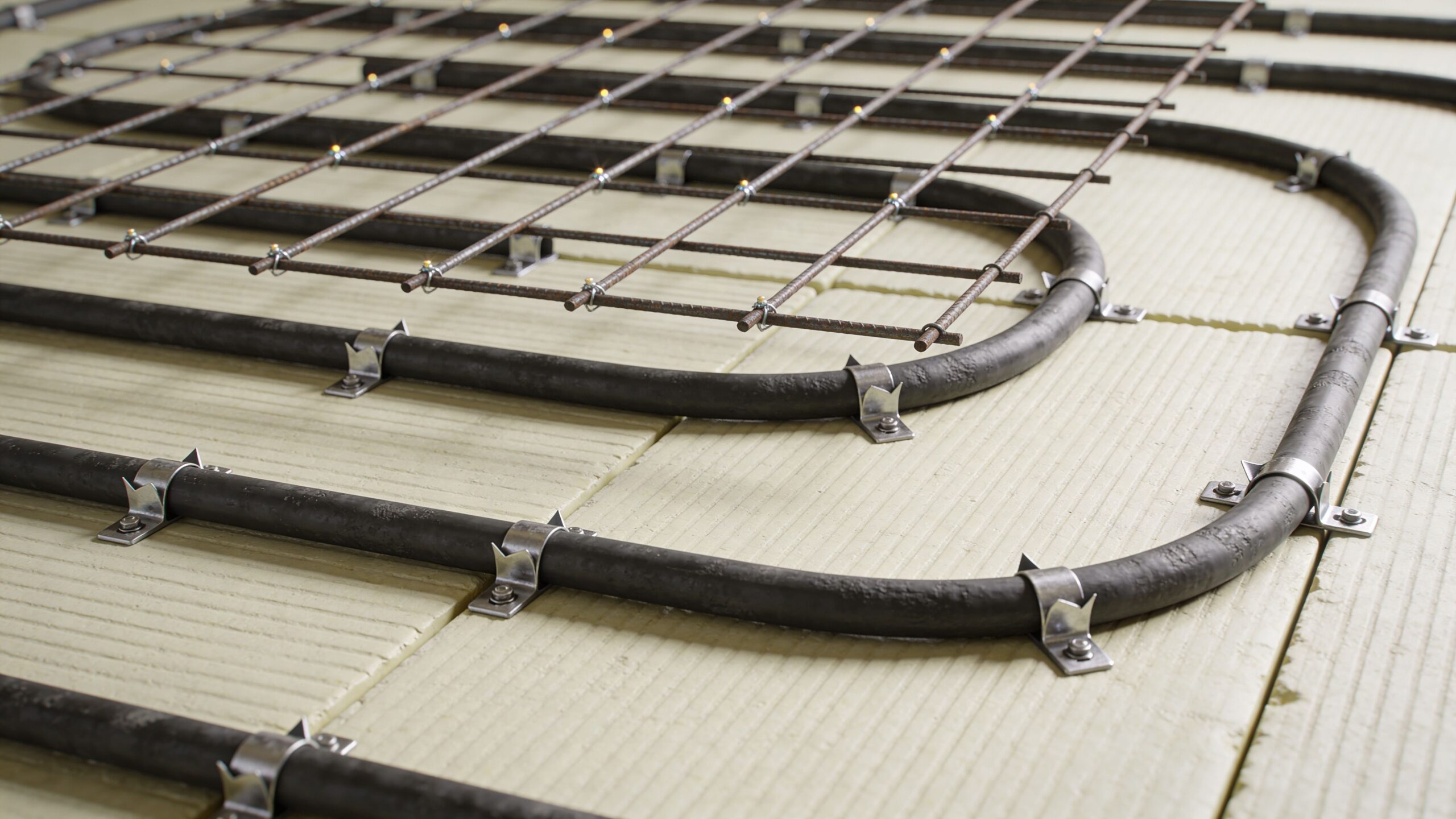 Installation af gulvvarmerør og armeringsnet på isoleringsplader til et nyt støbt betongulv under opbygning.