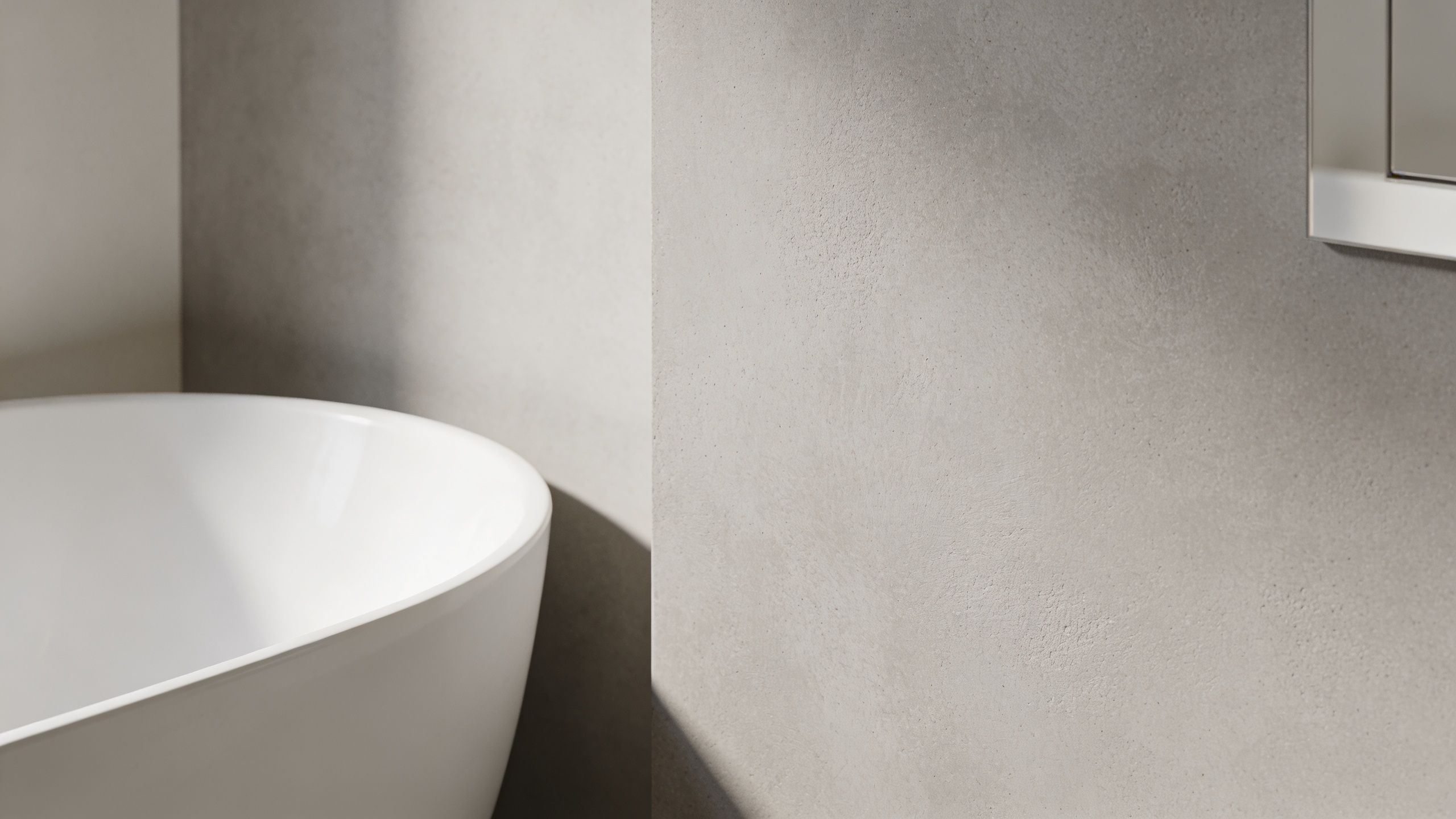 Nærbillede af et elegant hvidt badekar placeret foran en minimalistisk betonvæg i et moderne badeværelse.